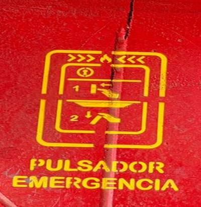 Señalización amarilla de pulsador de emergencia sobre superficie roja